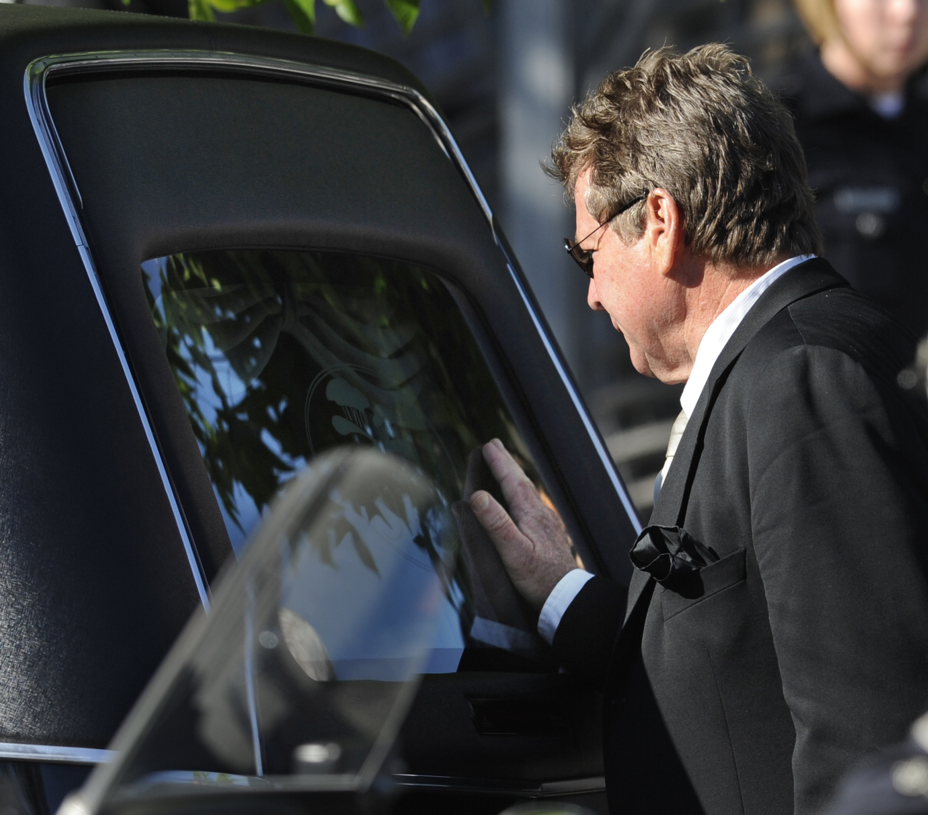 Ryan O’Neal touches the back of the hearse carrying Farrah Fawcett’s casket after her...