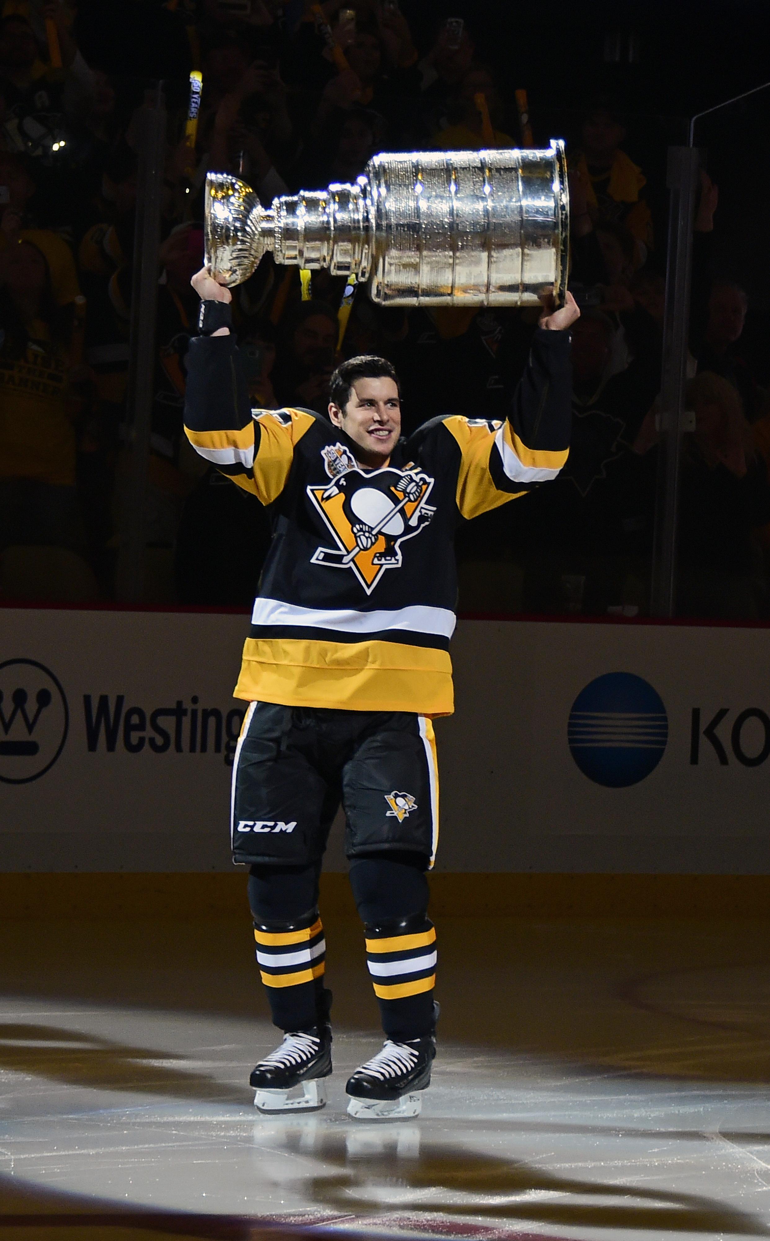 Pittsburgh Penguins center Sidney Crosby (87) brings the Stanley Cup to  center ice for the banner raising ceremony before the start of the home  opener against the St. Louis Blues at PPG