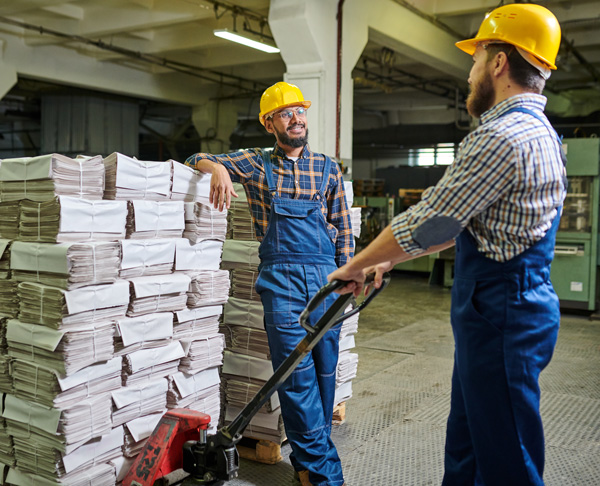 Couple of newspaper delivery folks hanging out with newspapers