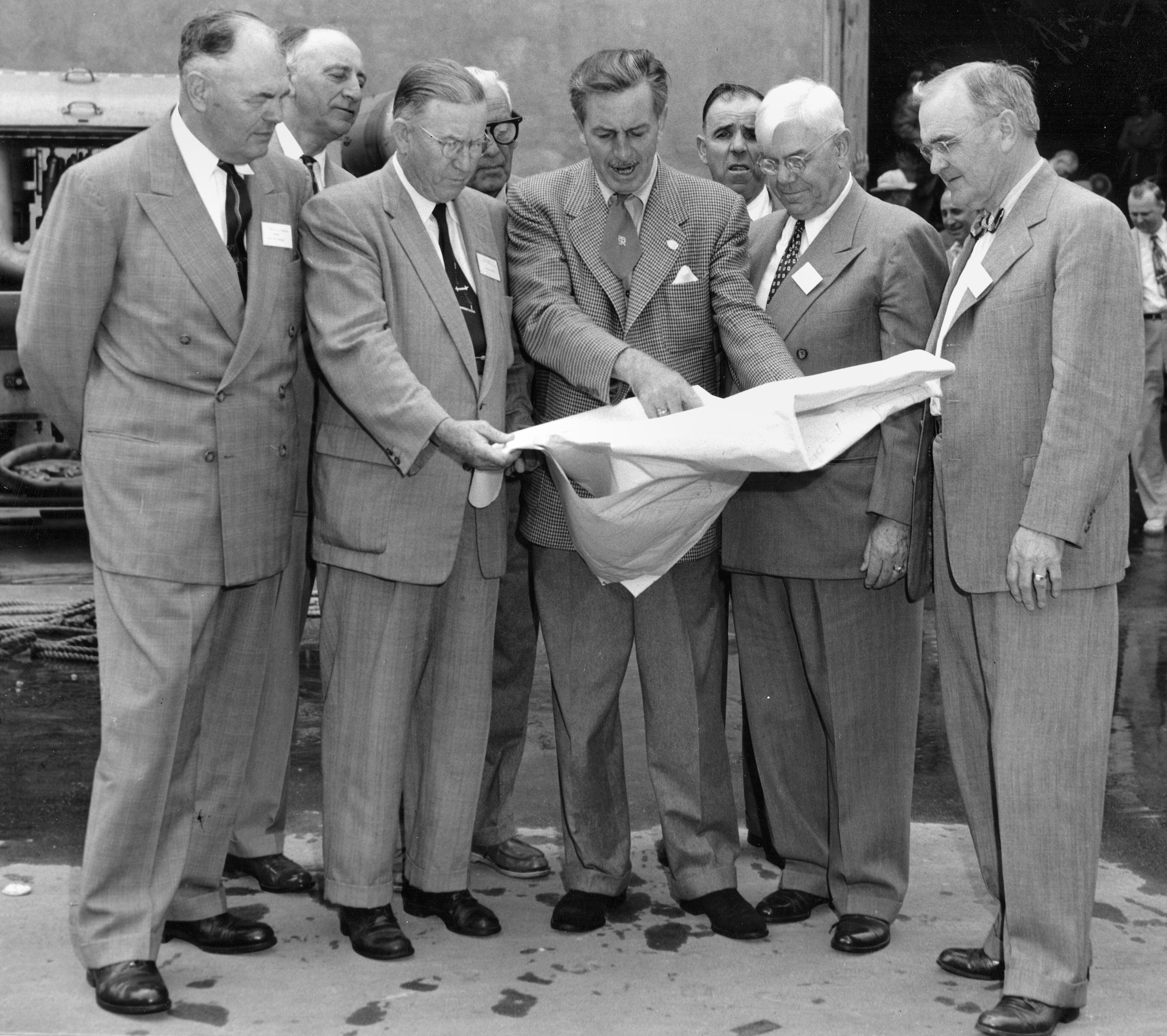 Walt Disney shows plans to officials of Orange County, Calif. The county had to change its building codes to allow for what Walt’s team came up with.